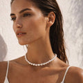 Woman wearing a pearl necklace against a neutral background