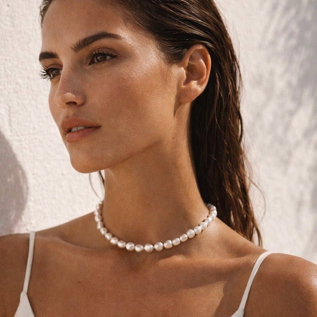 Woman wearing a pearl necklace against a neutral background