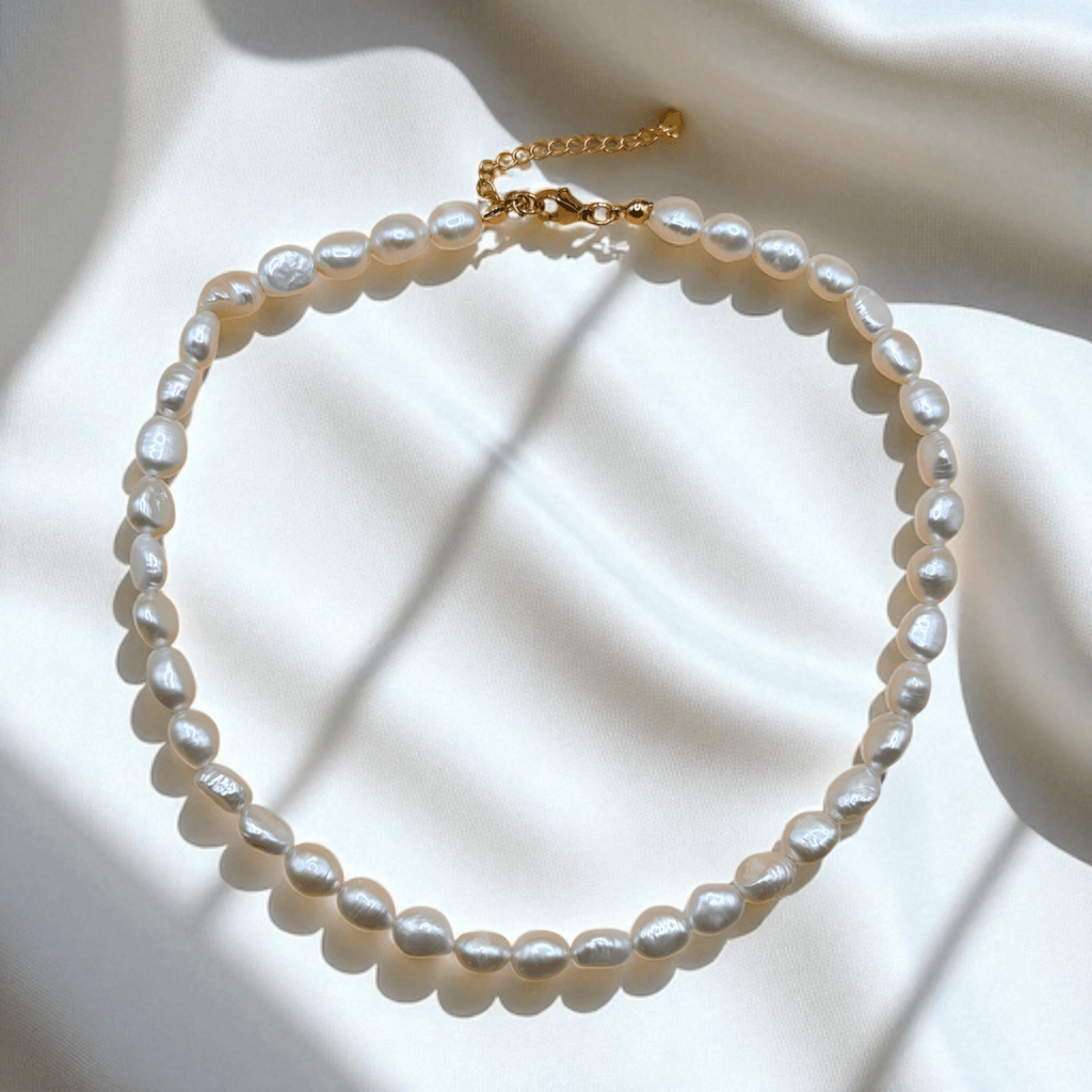 Pearl necklace with gold clasp on a soft white background